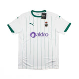 A white Puma Racing Santander home soccer jersey with green pinstripes, green collar and sleeve trim, featuring the purple Aldro sponsor logo on the front.