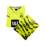 A folded Borussia Dortmund soccer kit set on a white background, featuring a neon yellow V-neck jersey with black and white trim, a black Puma logo, the BVB 09 crest, and a matching neon yellow and black patterned shorts.