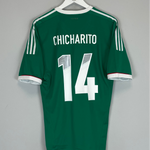 Green sports jersey with 'Chicharito' and number '14' on a hanger against a gray background