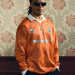 2024/25 Takeaway.com Cult Kits football jersey modeled in orange color with sunglasses against vintage wallpaper, part of Cult Kits collection.