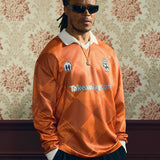 2024/25 Takeaway.com Cult Kits football jersey modeled in orange color with sunglasses against vintage wallpaper, part of Cult Kits collection.
